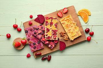 Handmade chocolate bars with fruits, berries and nuts on color wooden background