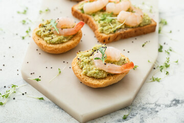 Tasty sandwiches with guacamole and shrimps on light background, closeup