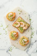 Tasty sandwiches with guacamole and shrimps on light background