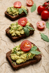 Tasty sandwiches with guacamole and tomato on table