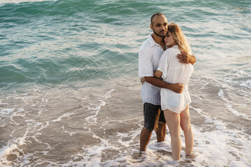 Beautiful young couple hugging on the beach by the water