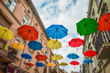 Colorful umbrellas hang between houses on the street