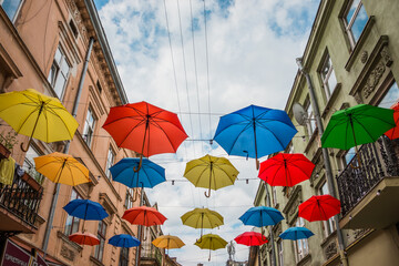 Fototapeta na wymiar Colorful umbrellas hang between houses on the street