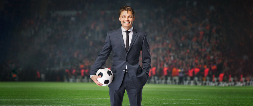 smiling businessman in formal wear with soccer ball in the big stage