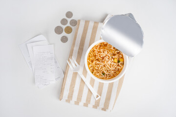Instant noodle cup with coin on a white table, Concept end of month not enough money