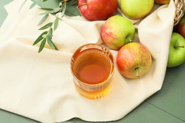 Glass of tasty apple juice on color wooden background