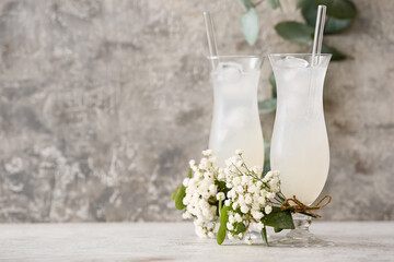Glasses with tasty cocktail and beautiful gypsophila flowers on light background