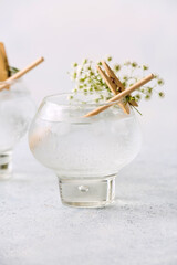 Glass with tasty cocktail and beautiful gypsophila flowers on light background