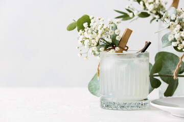 Glass with tasty cocktail and beautiful gypsophila flowers on light background