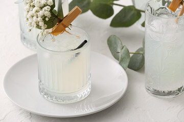 Glasses with tasty cocktail and beautiful gypsophila flowers on light background