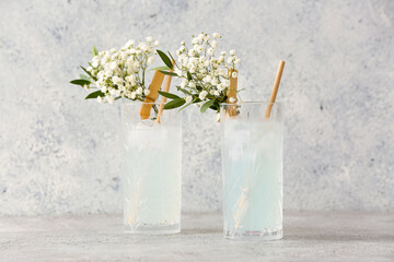 Glasses with tasty cocktail and beautiful gypsophila flowers on light background