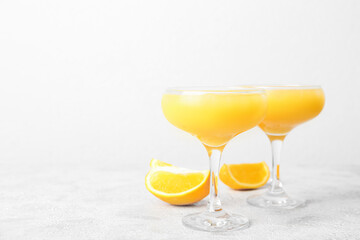 Glasses of orange margarita cocktail on light background