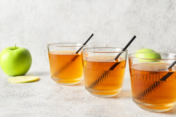 Glasses of apple juice on light background