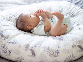 Closeup adorable infant Asian baby girl  try to sucking her feet and toes  to relaxing or sign for a baby developmental 4-8 months