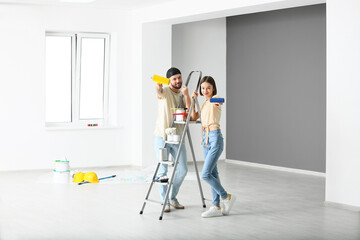 Young couple with painter's tools in their new house