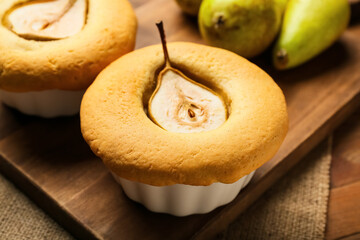 Board with tasty pear pot pies on wooden background
