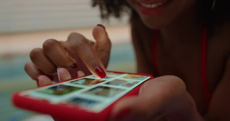 african american woman using smartphone by swimming pool browsing online scrolling social media picture gallery on mobile phone screen enjoying summer outdoors