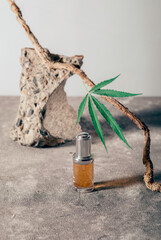 Glass bottle with CBD oil, THC tincture and hemp leaf on gray marble background. naturalness. CBD oil cosmetics.