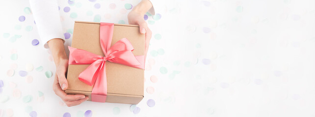 woman hands holding gift box with pink bow, confetti, small hearts
