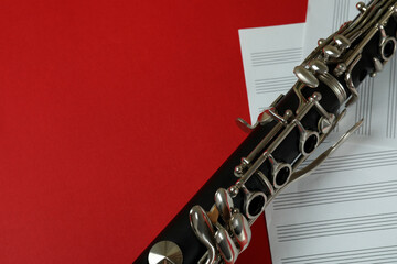 Clarinet and music sheets on red background