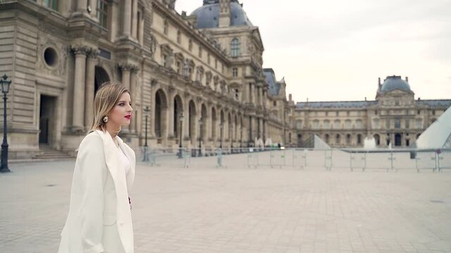 young stylish business woman in a white suit walks the streets of Paris France. Fashion businesswoman goes urban background of the ancient city of Europe. Exquisite lady in heels with red lipstick