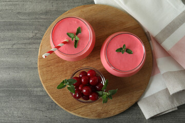 Glasses of cherry smoothie and ingredients on gray textured table