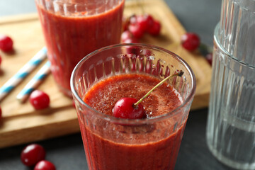 Glasses of cherry smoothie and ingredients on dark textured table