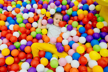 Boy kid playing and having a good time in a ball room. Little smiling child playing lying in...
