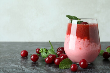 Glass of cherry smoothie and ingredients on black smokey table