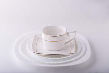 White empty cup with saucer and plates served on a white table.