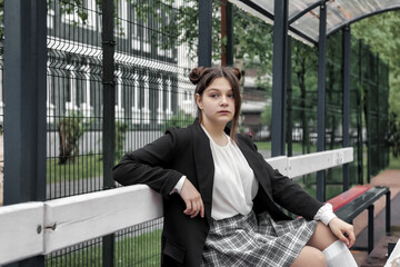 Portrait of thirteen-year-old schoolgirl in white blouse, plaid skirt and jacket at schoo