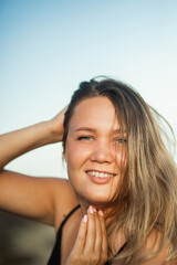 A large portrait of an attractive girl in nature. A girl with natural makeup and flowing hair seductively poses for the camera