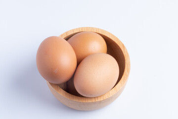 Three fresh eggs in a cup on a white background.