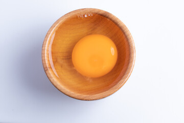 raw eggs in a wooden cup on a white background