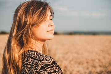 face profile of romantic young woman enjoying sunset on wheat field, girl breathe breathes deeply ,...