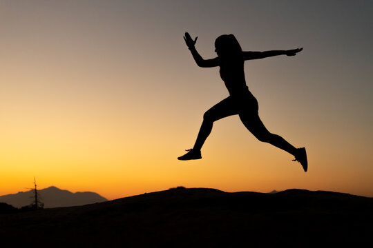 Silueta de atleta en la monta&ntilde;a con el atardecer, haciendo t&eacute;cnica de carrera. Espacio para texto.