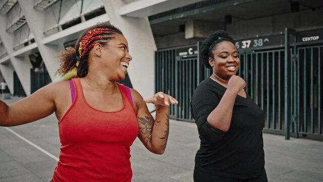 Morning walk concept. Two overweight african american female friends going together in urban area after cardio training