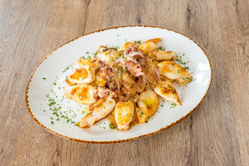 Great Spanish recipe for fried squid with their tips and caramelized onion on a white tray with chopped parsley