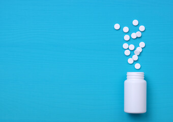 Pills, tablets and bottle on blue background.