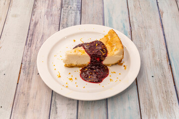 Cheesecake with blueberry syrup with orange zest on white plate
