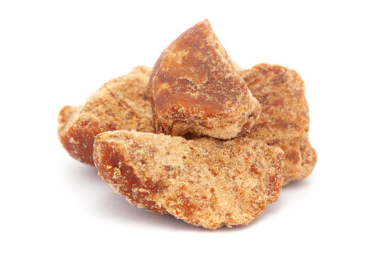 Micro close-up and details of Organic Indian sugarcane jaggery piece (gud) (Saccharum officinarum)  isolated over white background.
