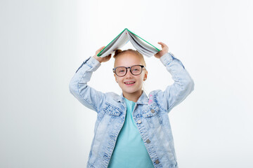 a little girl hold  book on her head on a white background is isolated
