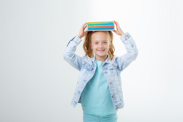 a little girl with a book on her head on a white background is isolated