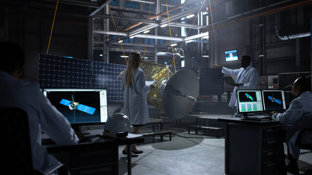 Engineer and Technician Working on Satellite Construction. Aerospace Agency: Diverse Team of Scientists Using Technological Equipment and Laptop Computer to Develop Spacecraft for Space Exploration.