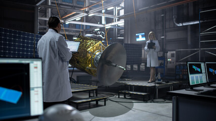 Engineer and Technician Working on Satellite Construction. Aerospace Agency: Diverse Team of Scientists Using Technological Equipment and Laptop Computer to Develop Spacecraft for Space Exploration.
