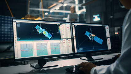 Male Engineer Uses Computer while Working on Satellite Construction. Aerospace Agency: Scientist is Using Computer Software for Programming and Assembly of Spacecraft for Space Exploration Mission.