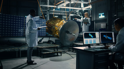 Engineer and Technician Working on Satellite Construction. Aerospace Agency: Diverse Team of Scientists Using Technological Equipment and Laptop Computer to Develop Spacecraft for Space Exploration.