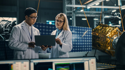 Engineer and Technician Working on Satellite Construction. Aerospace Agency: Diverse Team of Scientists Using Technological Equipment and Laptop Computer to Develop Spacecraft for Space Exploration.
