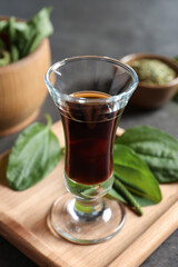 Glass of broadleaf plantain oil on wooden board