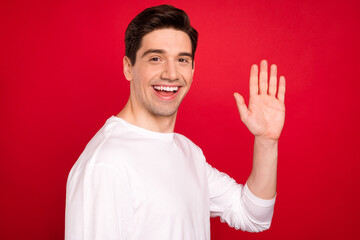Naklejka premium Photo portrait brunet in white clothes waving hand on meeting smiling isolated vivid red color background